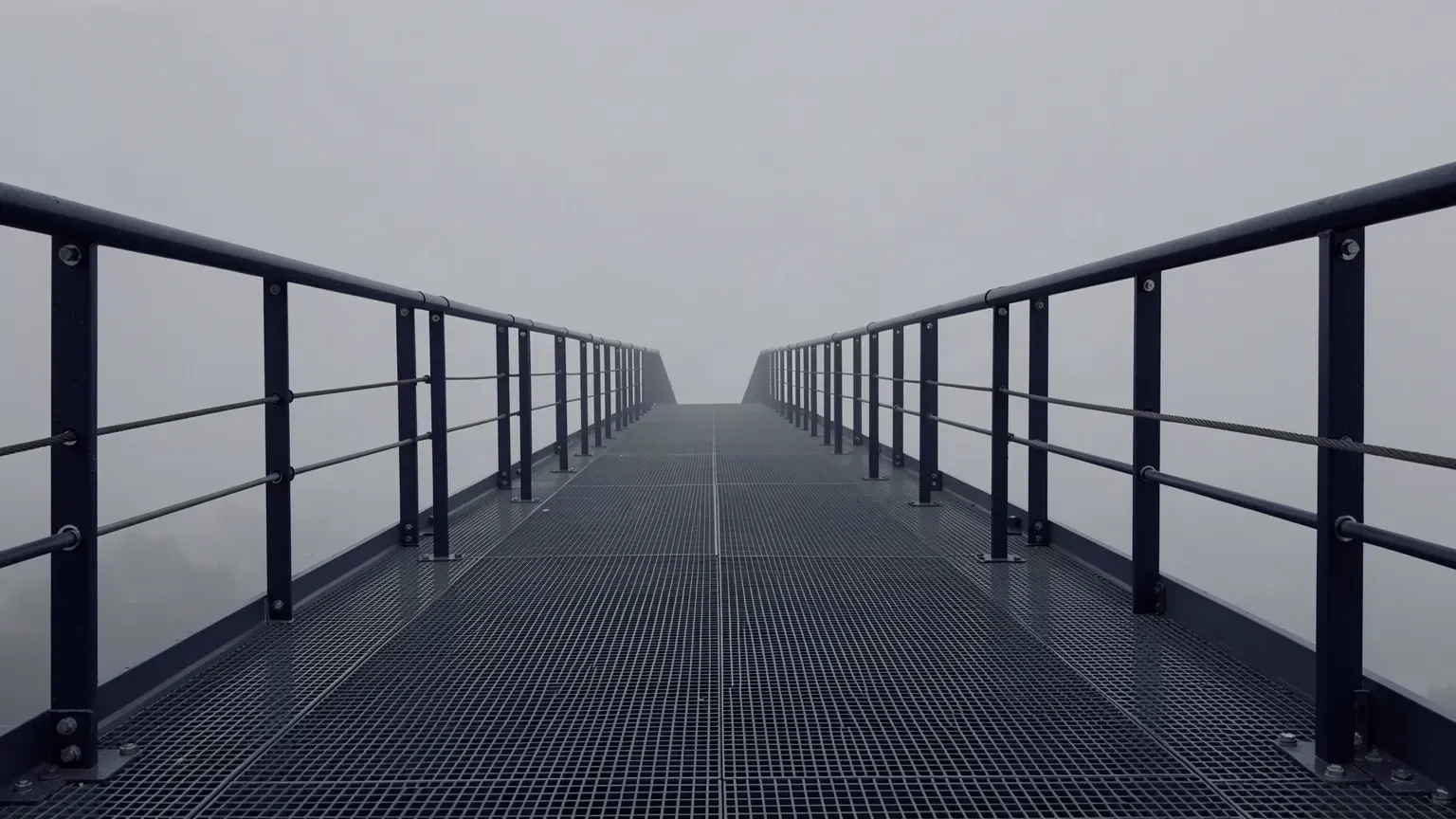 An empty steel access platform with handrails and safety cable runs.